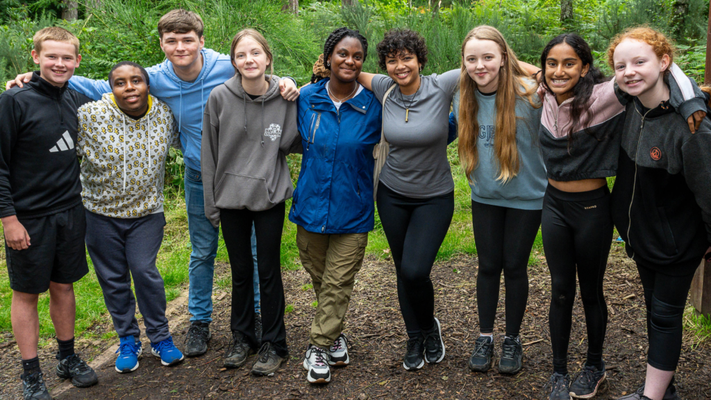 young people in a line smiling to camera in the forest