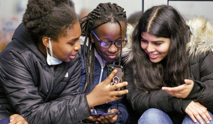 Image of three girls looking at a phone