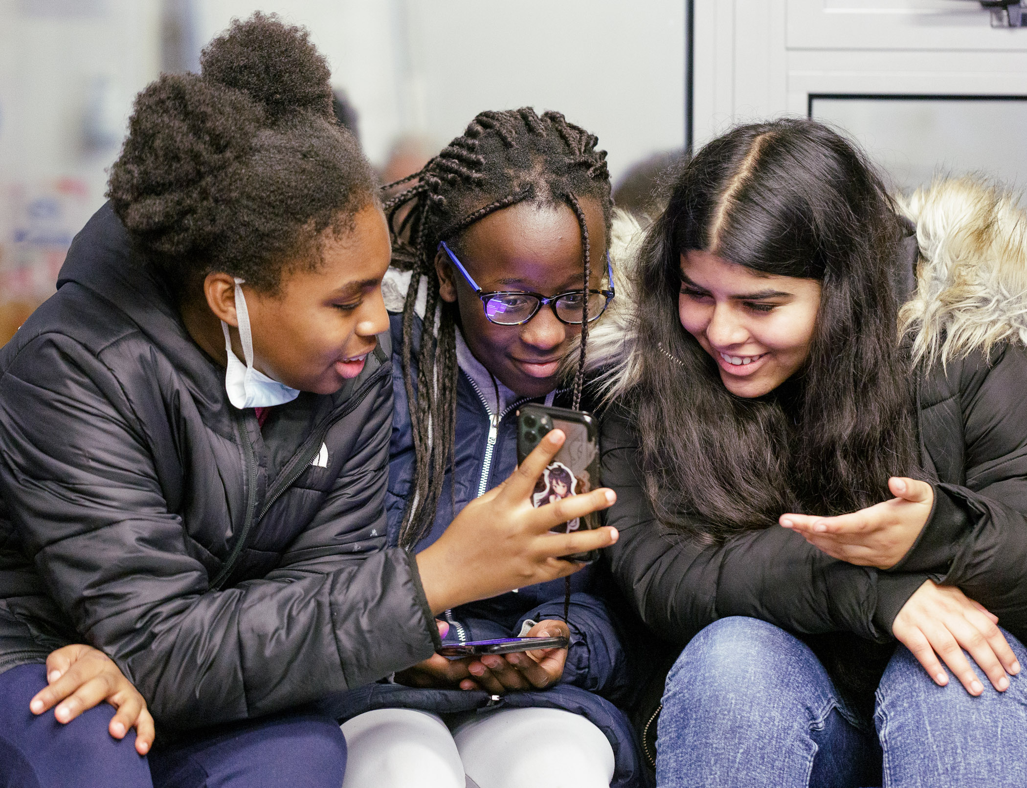 Image of three girls looking at a phone
